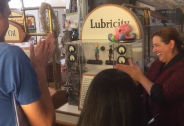 Adults clapping in front of a machine.