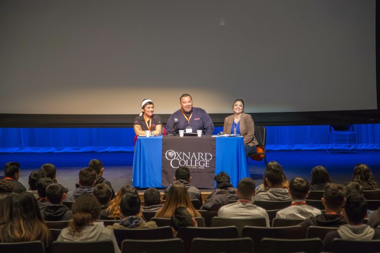 CRC employee sits on a panel in front of a crowd at an Oxnard College event.