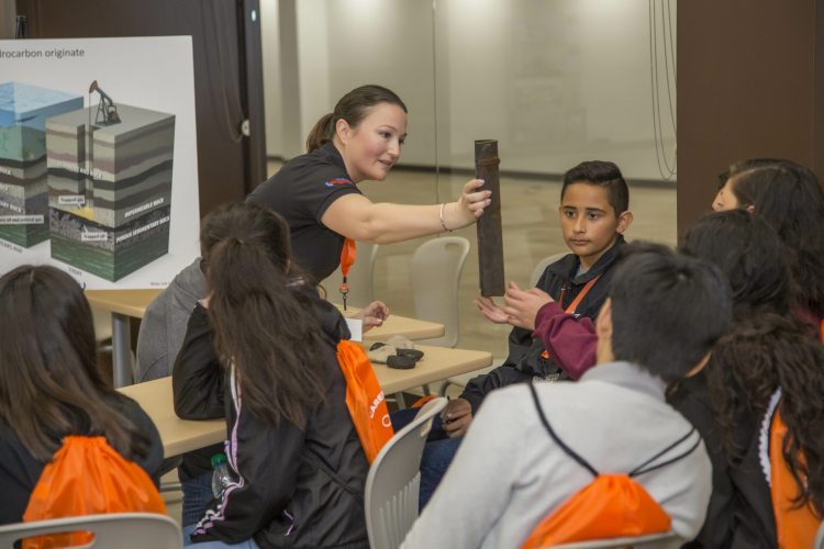 CRC employee hands students an old pipe to teach them about oil and gas production.