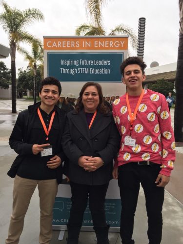 Teacher stands with students in front of a Careers in Energy STEM banner.
